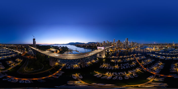 Aerial view of Burrard Street Bridge and illuminated Vancouver skyline at twilight, featuring a marina with boats in False Creek, Metro Vancouver A, British Columbia, Canada.