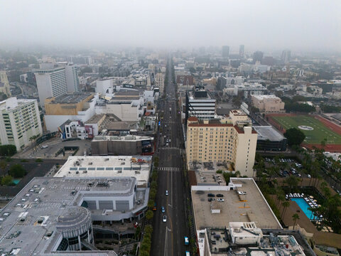 Aerial view of Hollywood Boulevard and the Hollywood Walk of Fame, featuring urban buildings, palm trees, and city streets under a hazy sky in Los Angeles, California, United States.