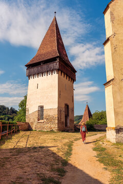 Woman walking beside historic defensive tower at Biertan fortified church in Romania
