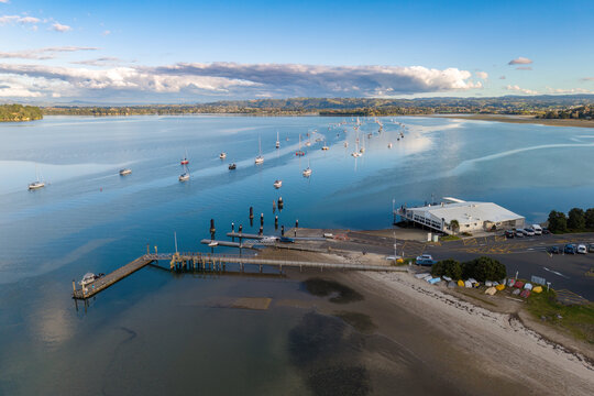Omokoroa, New Zealand. An aerial view of the jetty and a row of yachts moored in the calm waters of Tauranga Harbour