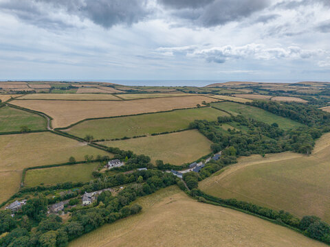Aerial view of agricultural farmland with hedgerows, tracks, and harvested fields in the rural landscape of Looe, Cornwall, United Kingdom.