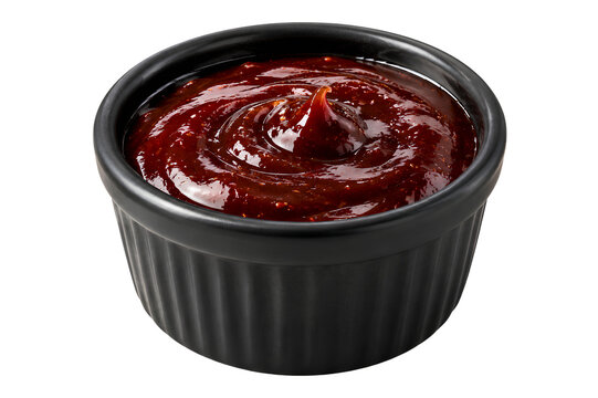 Spicy ketchup swirl with glossy texture in black bowl on transparent background
