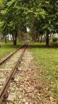 Eye level view of abandoned railway tracks running through a green park during daytime in Hanoi, Vietnam