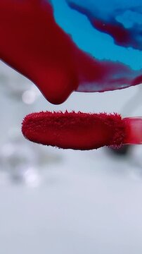Close up of a brush with red liquid poured onto it. Beauty product concept for lipstick or lip tint to redden lips. Cosmetic application.