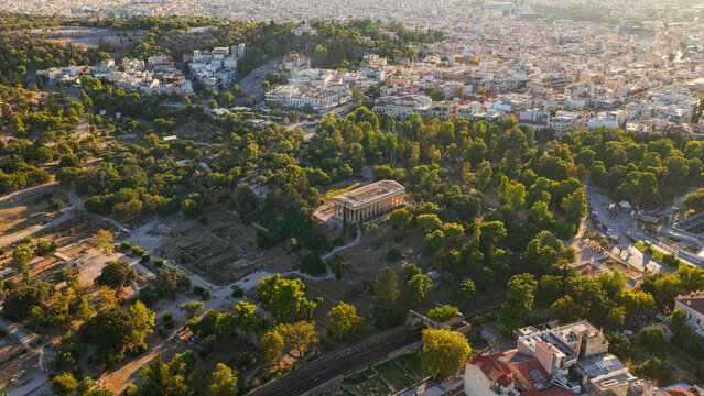 Aerial view of the Temple of Hephaestus surrounded by lush trees and the historic urban landscape of Athens, Greece.