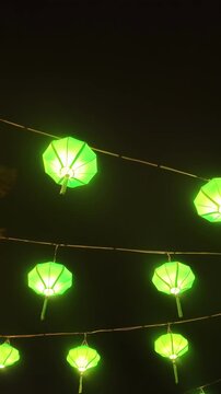 Low angle view of illuminated green silk lanterns hanging along a street at night in Hoi An Ancient Town, Vietnam
