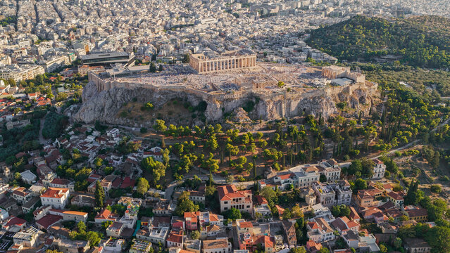 Aerial view of the Acropolis of Athens featuring the Parthenon and ancient ruins surrounded by the dense urban landscape and greenery of Athens, Greece.