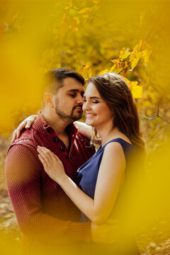 Young couple embracing in autumn forest setting.