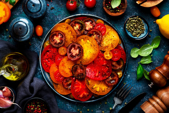 Heirloom tomato salad, healthy food vegetarian vegetable mix near lemon and wooden pepper mill. Mediterranean diet and holistic wellness lifestyle concept. Fresh plant based autumn homemade dinner.