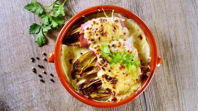 Title SEO
Baked Chicory Gratin Wrapped in Ham With Melted Cheese in Ceramic Dish Top View