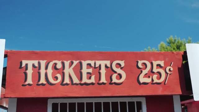 A vintage 25 cent tickets sign is captured in a captivating close-up, revealing its weathered charm and nostalgic appeal under bright sky.