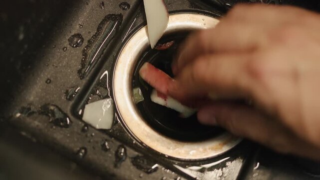 A motion clip showing a person disposing potato peels down a kitchen sink drain, showcasing efficient waste management.
