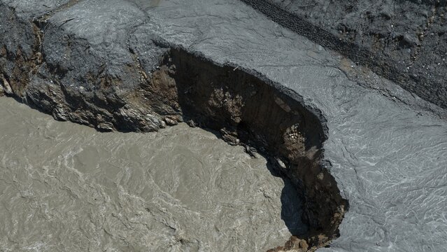 Aerial view of severe riverbank erosion showing exposed earth and sediment-laden water along the river in Betrawoti Bazaar, Bagmati Province, Nepal.