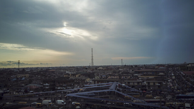 Aerial view of Agege featuring dense urban rooftops, a prominent communication tower, and busy streets under a dramatic cloudy sky in Lagos, Lagos, Nigeria.