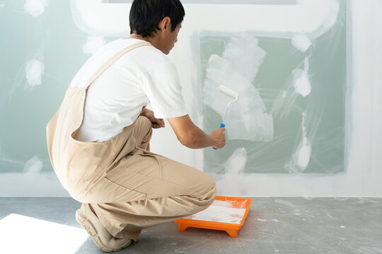 painter man, brush in hand for products to restore and paint the wall, indoor the building site of a house, wall during painting, renovation, painting, contractor, Architect, construction worker
