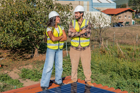 Multicultural solar engineers installing renewable energy panels on rooftop