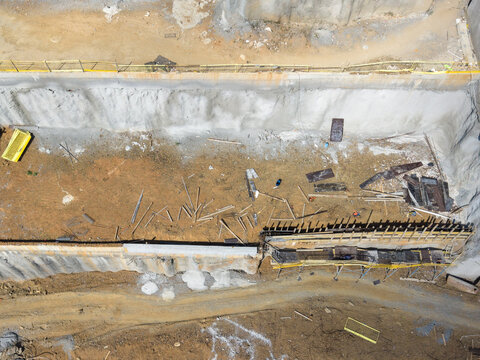 Aerial view of a deep construction site excavation with concrete retaining walls, scattered building materials, and scaffolding in Istanbul, Istanbul, Turkiye.