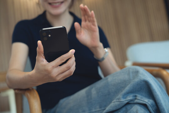 Woman using smartphone, waving her hand during video call with her friend, modern people lifestyle