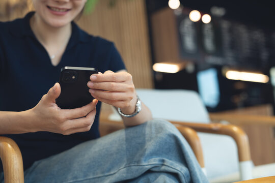 A woman smiling during using smartphone for social network at cafe, modern people lifestyle