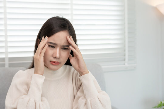 Headache, female having migraine pain, bad health, Asian woman feeling stress and headache, Office syndrome, sad tired touching forehead having migraine or depression, irritated girl, sadness grief