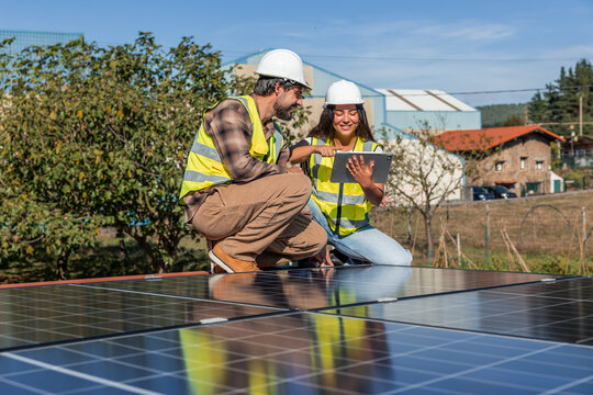 Multicultural engineers checking solar panels on rooftop