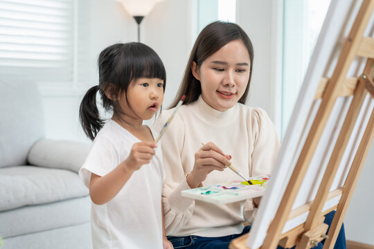 Happy mother playing learning paint for little girl. Funny family is happy and excited in the house. Mother and daughter  having fun spending time together. Holiday, Activity