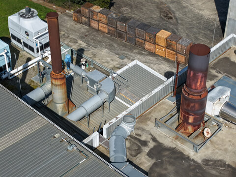 Aerial view of Rowville factory machinery featuring industrial exhaust pipes, ventilation units, and rows of wooden storage crates on a metal rooftop in Melbourne, VIC, Australia.
