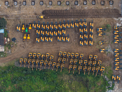 Aerial view of numerous yellow excavators parked in organized rows at a construction site in Chakan, Maharashtra, India.