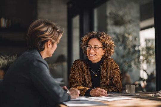 Smiling businesswomen discussing ideas in a modern office meeting