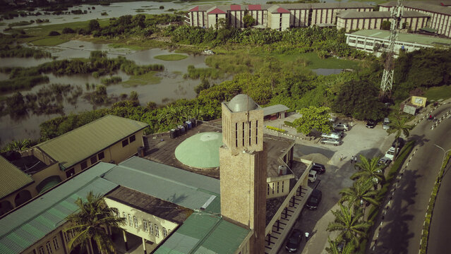 Aerial view of the University of Lagos campus featuring its iconic tower, green-roofed buildings, surrounding lush vegetation, and nearby wetlands in Lagos, Lagos, Nigeria.