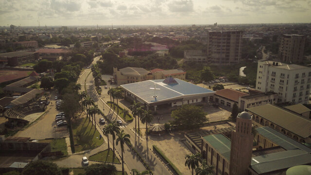 Aerial view of the University of Lagos campus featuring the Chapel of Christ the Light surrounded by palm trees, paved roads, and urban buildings in Lagos, Lagos, Nigeria.