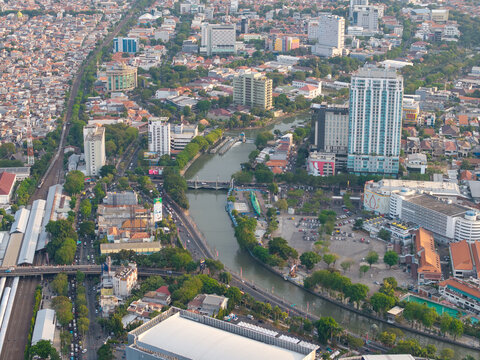 Surabaya, Indonesia - 28 August 2026: Aerial view of the Kalimas River flowing through Surabaya, East Java, surrounded by high-rise buildings, dense urban housing, and green trees.