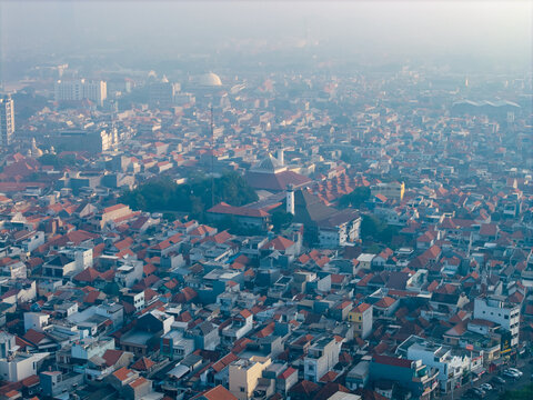 Genteng, East Java, Indonesia - 13 August 2026: Aerial view of Surabaya Old Town with dense historic rooftops, narrow streets, and traditional mosque architecture under a hazy sky.