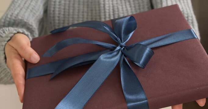 Woman hands holding and showing gift box with blue satin ribbon close up video