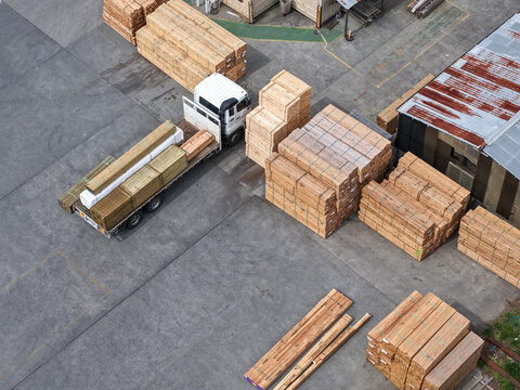 Melbourne, Australia - 25 September 2026: Aerial view of a truck loaded with stacks of lumber in a factory yard with wooden pallets and industrial machinery.