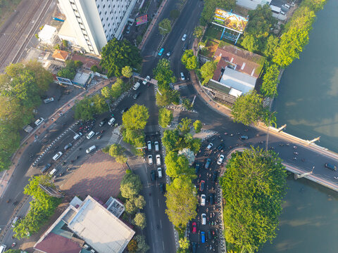 Surabaya, Indonesia - 05 August 2026: Aerial view of a busy urban intersection with heavy traffic, motorcycles, and cars crossing a bridge over a river.