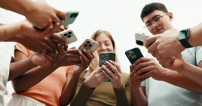 Happy, students and hands with phone for online chatting, communication or data sync together. Low angle, group or friends typing with technology for mobile conversation, social media or texting app