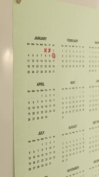 Close up video of woman hand crossing out calendar dates with red marker.