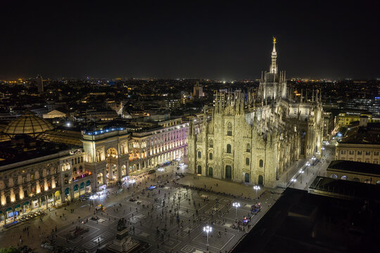 Milan, Italy - 23 September 2026: Aerial view of the illuminated Duomo di Milano and Piazza del Duomo at night, featuring gothic architecture and surrounding historic buildings.