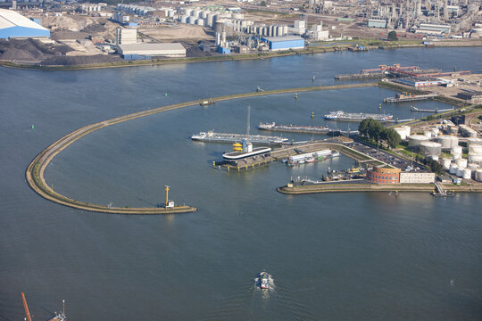 Rotterdam, Netherlands - 03 September 2014: Aerial view of Rotterdam Harbour featuring industrial infrastructure, storage tanks, and cargo ships navigating the waterway.