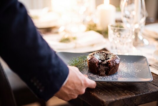 Waiter serving a warm chocolate lava cake with molten center on a festive holiday dinner table