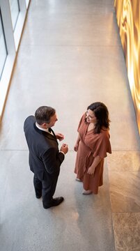 High angle view of an elegant couple standing and talking in a modern luxury hallway during a formal event