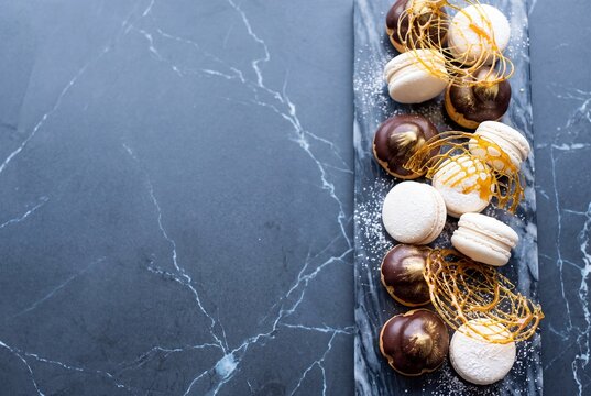 Assorted French Macarons and Chocolate Profiteroles Decorated with Spun Sugar on a Marble Platter