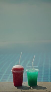 Two refreshing slushy drinks by poolside on a sunny day.