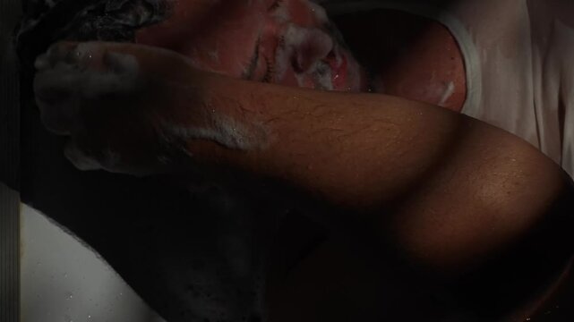 A man grooms himself while lying in the bathtub