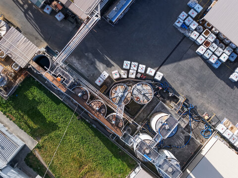 Melbourne, VIC, Australia - 22 September 2026: Aerial view of an industrial facility in Kilsyth featuring large storage tanks, metal piping, and rows of white containers in the yard.