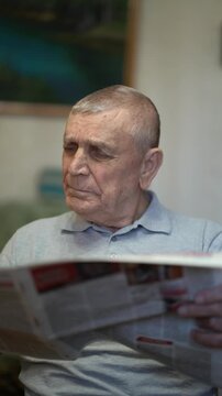 Elderly man reading a newspaper at home, enjoying a quiet and peaceful moment of daily life.