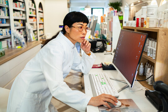 Pharmacist working on computer at pharmacy counter