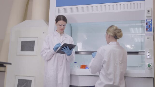 Two lab technicians work together in a modern laboratory with microscopes and samples during a research session