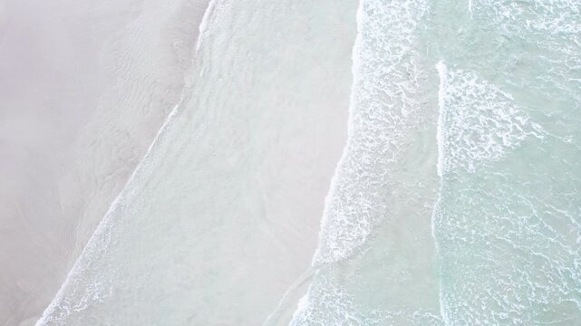 Top down static drone shot of ocean waves washing shore The Concept of coastal tranquility